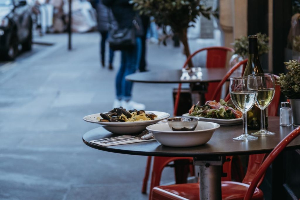 Detail of plates of food and glasses of wine on outdoor dining table for two