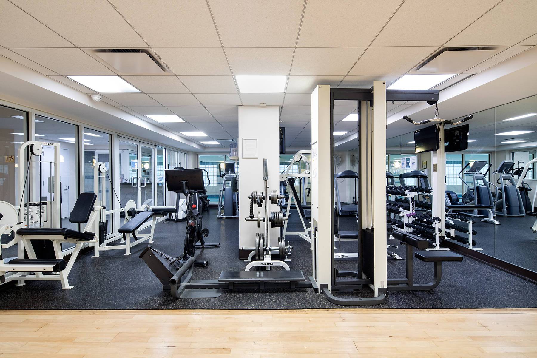 Bright fitness center with mirrored wall, weights and fitness equipment