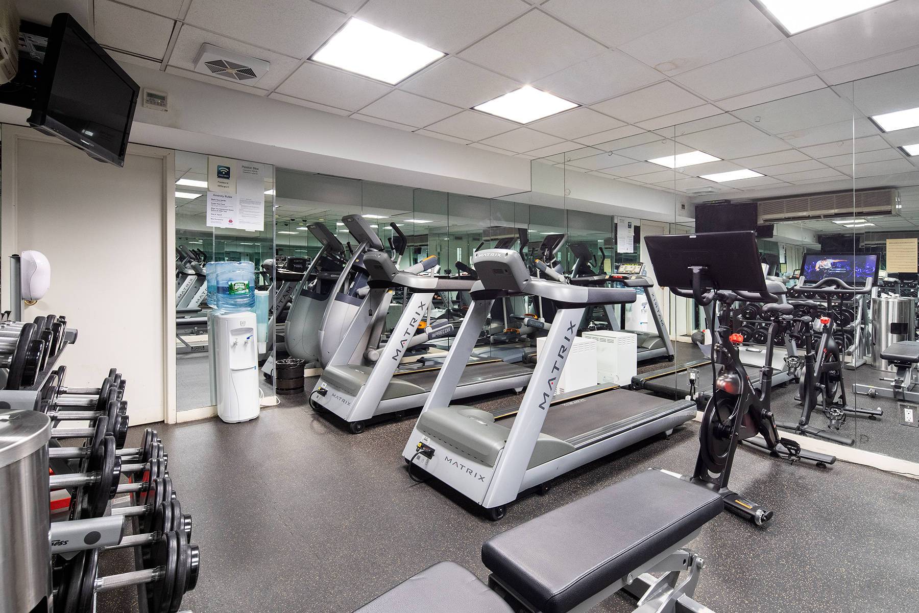 Fitness center with mirrored walls, television, treadmills, bench and bike