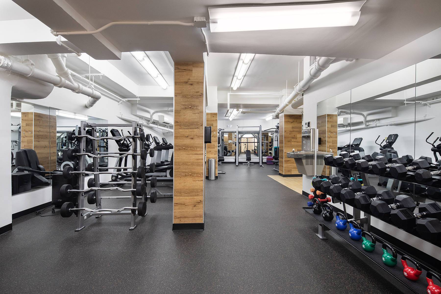 Spacious fitness center with numerous weights, lifting areas, equipment and mirrored walls